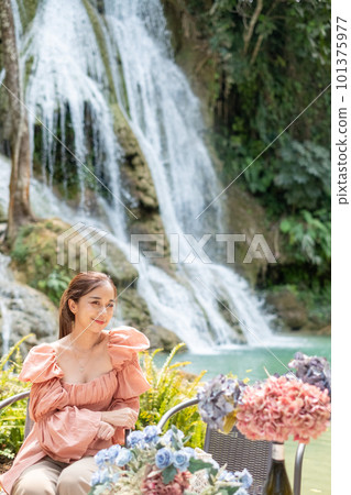Young Asian woman sitting on a chair In front of the Khoun Moung Keo Waterfall 101375977