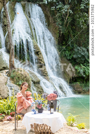 Young Asian woman sitting on a chair In front of the Khoun Moung Keo Waterfall 101375982