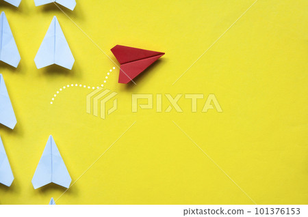 Top view of red paper airplane origami leaving other white airplanes on yellow background with customizable space for text or ideas. Leadership skills concept and copy space. Top view of red paper airplane origami leaving other white airplanes on yellow background with customizable space for text or ideas. Leadership skills concept and copy space. 101376153