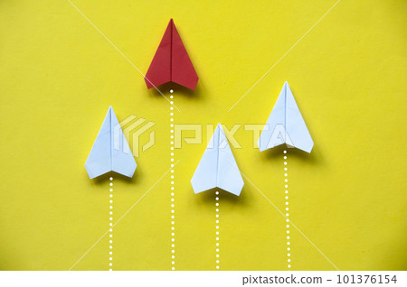 Top view of red paper airplane origami leaving other white airplane behind on yellow background 101376154