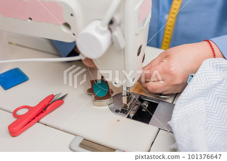 Atelier process needle detail. Unrecognizable woman hand on a sewing machine doing handmade fabric Atelier process needle detail. Unrecognizable woman hand on a sewing machine doing handmade fabric 101376647