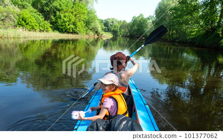 Family kayak trip. Mom and daughter rowing a boat on the river, a water hike, a summer adventure. Eco-friendly and extreme tourism, active and healthy lifestyle Family kayak trip. Mom and daughter rowing a boat on the river, a water hike, a summer adventure. Eco-friendly and extreme tourism, active and healthy lifestyle 101377062