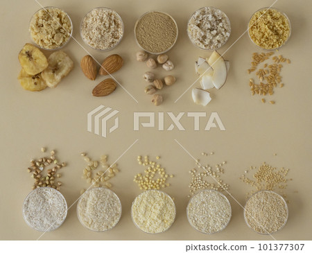 Various gluten-free flours - chickpeas, brown rice, green buckwheat, almonds, coconut, banana, flax, millet, amaranth, quinoa on a beige background. Top view with a copy of the space 101377307