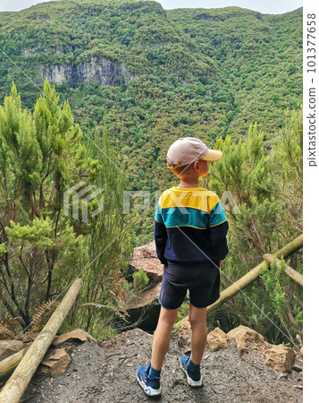 Boy stands with his back against background of the greenery mountain. Boy stands with his back against background of the greenery mountain. 101377658