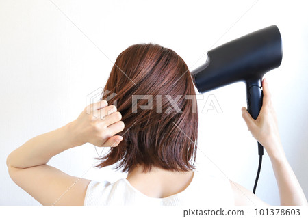 A woman drying her hair with a hair dryer 101378603