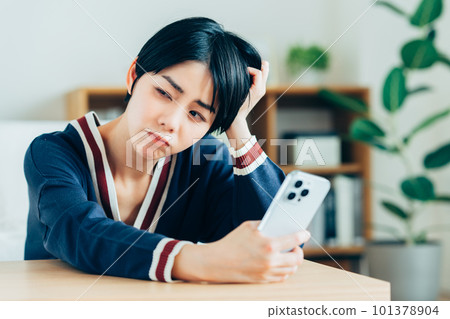Young woman worried about looking at smartphone Young woman worried about looking at smartphone 101378904