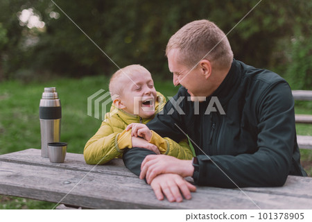 Happy Family: Father And Child Boy Son Playing And Laughing In Autumn Park, Sitting On Wooden Bench And Table. Father And Little Kid Having Fun Outdoors, Playing Together. Father And Son Sitting On A 101378905