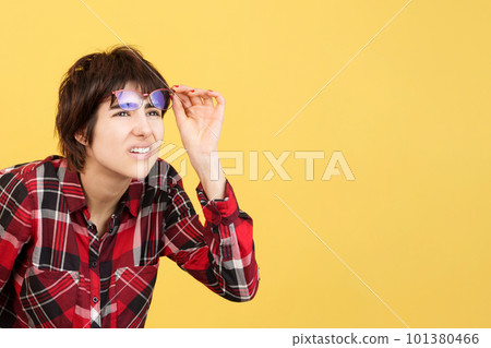 Androgynous person taking off her glasses to look away Androgynous person taking off her glasses to look away 101380466