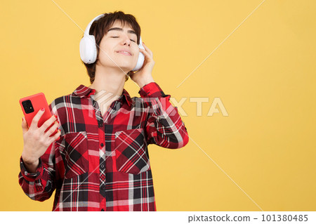 Relaxed androgynous person listening to music with mobile and headphones Relaxed androgynous person listening to music with mobile and headphones 101380485