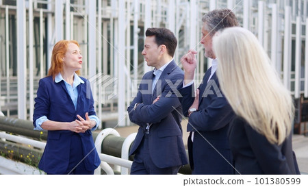 Redhead businesswoman talking with a group of business people outdoors 101380599