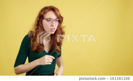 Redheaded woman with glasses spying with curiosity 101381108