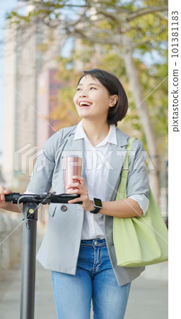 woman walking on electric scooter woman walking on electric scooter 101381183