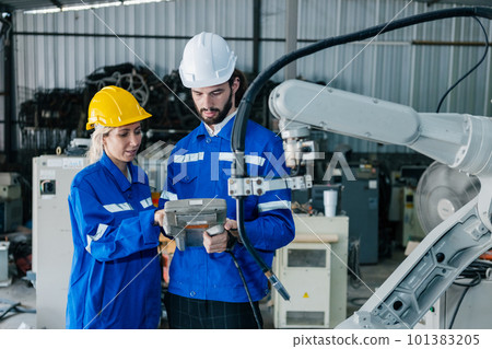 Team engineer using remote robot controller operate standing at automation robot arms machine Team engineer using remote robot controller operate standing at automation robot arms machine 101383205