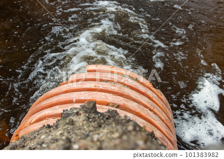 A stream of water flows from a large flexible pipe - hose. A stream of water flows from a large flexible pipe - hose. 101383982