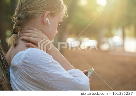 Portrait of teenage girl in white shirt and headphones typing on mobile phone Portrait of teenage girl in white shirt and headphones typing on mobile phone 101385227