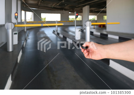 A hand using a remote control opens an automatic barrier in a parking lot. A hand using a remote control opens an automatic barrier in a parking lot. 101385300