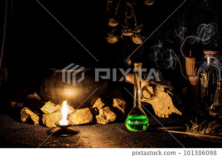 Witchs altar with goats skull, burning candle, dry herbs and witchcraft potion in vessel in the dark, low key, selective focus. Witchs altar with goats skull, burning candle, dry herbs and witchcraft potion in vessel in the dark, low key, selective focus. 101386098