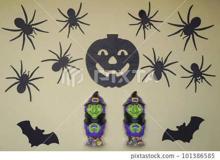 Scary Halloween figurines stand on a light background in close-up, behind hangs terrible pumpkin, spiders and bat 101386585