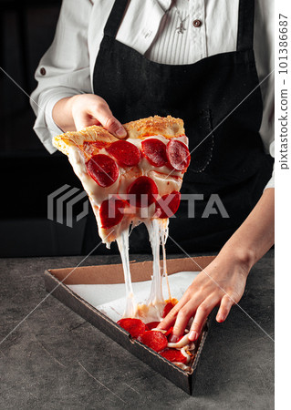 Baker tearing off a slice of pepperoni pizza Baker tearing off a slice of pepperoni pizza 101386687