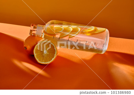 Glass water bottle with lemon on orange background. Glass water bottle with lemon on orange background. 101386980
