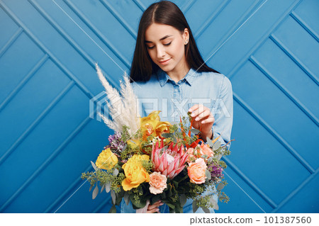 Florist with flowers. Woman makes a bouquet. Girl on a blue background 101387560