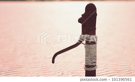 Rusty old metal water pump on sand beach 101390561