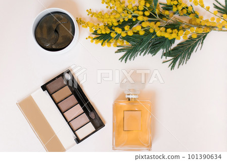 Flat lay fashion blogger. Decorative cosmetics and perfume, eye patches and a branch of yellow mimosa flowers on a white background 101390634