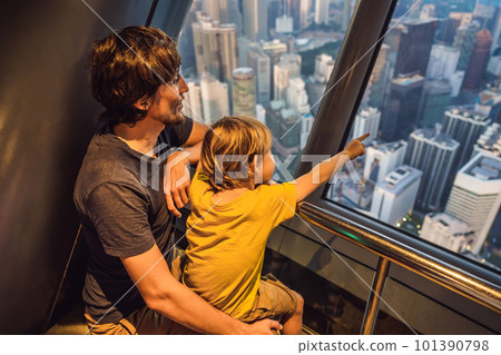Dad and son are looking at Kuala lumpur cityscape. Panoramic view of Kuala Lumpur city skyline evening at sunset skyscrapers building in Malaysia. Traveling with kids concept 101390798