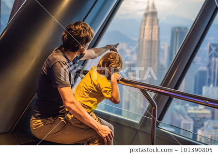 Dad and son are looking at Kuala lumpur cityscape. Panoramic view of Kuala Lumpur city skyline evening at sunset skyscrapers building in Malaysia. Traveling with kids concept Dad and son are looking at Kuala lumpur cityscape. Panoramic view of Kuala Lumpur city skyline evening at sunset skyscrapers building in Malaysia. Traveling with kids concept 101390805