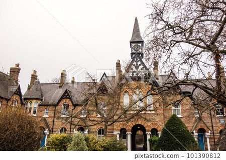 一座大型歷史建築，有一座磚砌鐘樓和帶樹枝的冬季樹木倫敦郊區溫莎的街道 101390812