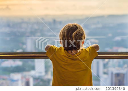 Little boy looks at Kuala lumpur cityscape. Panoramic view of Kuala Lumpur city skyline evening at sunset skyscrapers building in Malaysia. Traveling with kids concept Little boy looks at Kuala lumpur cityscape. Panoramic view of Kuala Lumpur city skyline evening at sunset skyscrapers building in Malaysia. Traveling with kids concept 101390840