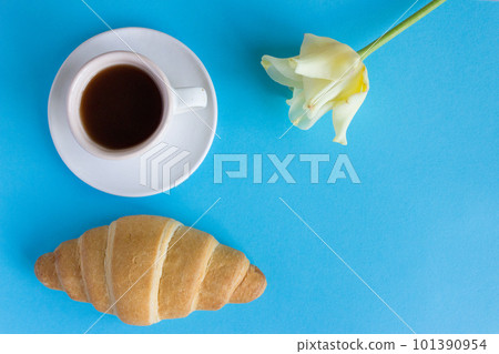 cup of coffee on a blue background, a tulip flower and a french croissant. breakfast concept cup of coffee on a blue background, a tulip flower and a french croissant. breakfast concept 101390954