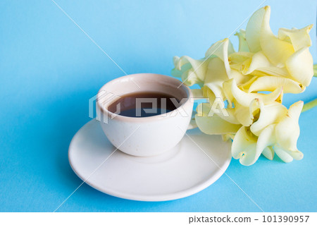 White cup of coffee on a blue background, flower. Morning breakfast White cup of coffee on a blue background, flower. Morning breakfast 101390957