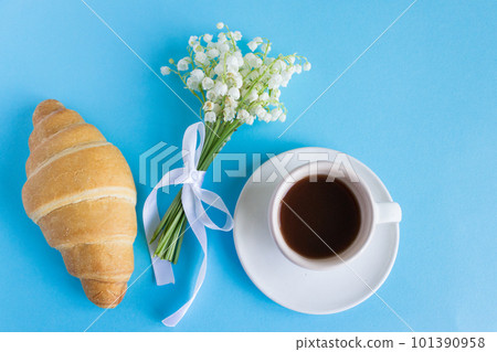 Coffee mug, bouquet of lily of the valley flowers, beautiful breakfast top view. croissant and coffee Coffee mug, bouquet of lily of the valley flowers, beautiful breakfast top view. croissant and coffee 101390958
