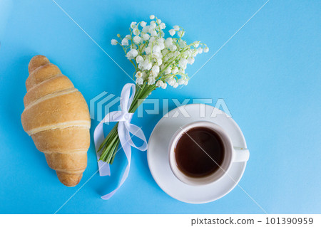 Coffee mug, bouquet of lily of the valley flowers, beautiful breakfast top view. croissant and coffee Coffee mug, bouquet of lily of the valley flowers, beautiful breakfast top view. croissant and coffee 101390959