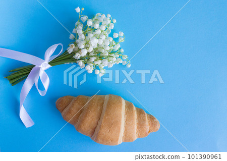 French croissant on blue background with lily of the valley. Breakfast French croissant on blue background with lily of the valley. Breakfast 101390961