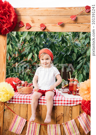 Lemonade Stand. Adorable little girl trying to sell lemonade. strawberry lemonade with ice and mint as summer refreshing drink in jars. Cold soft drinks with fruit. Child drinking smoothie in jar 101391241