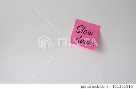 Slow down symbol. Pink steaky note with words Slow down. Beautiful white background. Business and Slow down concept. Copy space. Slow down symbol. Pink steaky note with words Slow down. Beautiful white background. Business and Slow down concept. Copy space. 101391510
