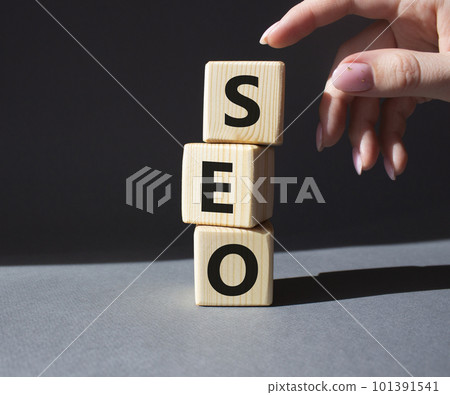 SEO - Search Engine Optimization symbol. Wooden blocks with words SEO. Businessman hand. Beautiful grey background. Business and SEO concept. Copy space. SEO - Search Engine Optimization symbol. Wooden blocks with words SEO. Businessman hand. Beautiful grey background. Business and SEO concept. Copy space. 101391541