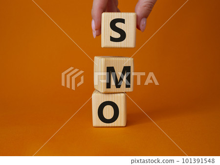 SMO - Social Media Optimization symbol. Wooden blocks with words SMO. Businessman hand. Beautiful orange background. Business and SMO concept. Copy space. 101391548