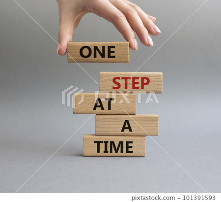 One step at a time symbol. Concept words One step at a time on wooden blocks. Beautiful grey background. Businessman hand. Business and One step at a time concept. Copy space. 101391593