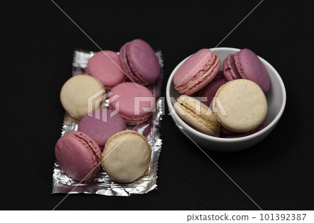 Macaroons on a shiny wrapper. Colorful delicious macaroons on a black background. Shiny cookie wrapper. 101392387