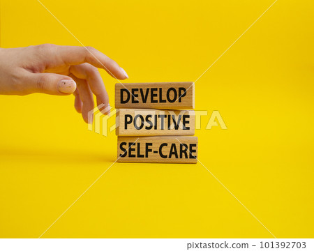 Develop positive self-care symbol. Concept words Develop positive self-care on wooden blocks. Beautiful yellow background. Businessman hand. Business and Develop positive self-care concept. Copy space 101392703