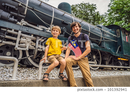 Father and son travelers in malaysia with malaysia flag celebrating the Malaysia independence day and Malaysia day. Travel to Malaysia concept Father and son travelers in malaysia with malaysia flag celebrating the Malaysia independence day and Malaysia day. Travel to Malaysia concept 101392941