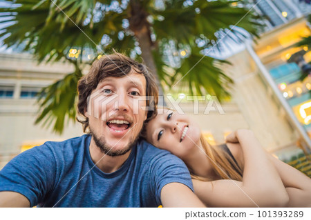 Travel, vacation and holiday concept - Happy couple having fun taking selfie over park with palms background and skyscrapers Travel, vacation and holiday concept - Happy couple having fun taking selfie over park with palms background and skyscrapers 101393289