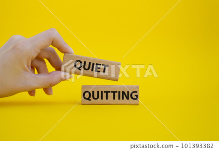 Quiet quitting symbol. Concept word Quiet quitting on wooden blocks. Beautiful yellow background. Businessman hand. Business and Quiet quitting concept. Copy space. Quiet quitting symbol. Concept word Quiet quitting on wooden blocks. Beautiful yellow background. Businessman hand. Business and Quiet quitting concept. Copy space. 101393382