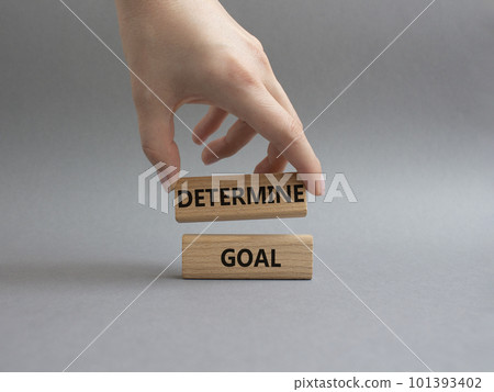 Determine goal symbol. Wooden blocks with words Determine goal. Beautiful grey background. Businessman hand. Business and Determine goal concept. Copy space. 101393402