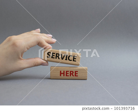 Service here symbol. Concept words Service here on wooden blocks. Beautiful grey background. Businessman hand. Business and Service here concept. Copy space. 101393716