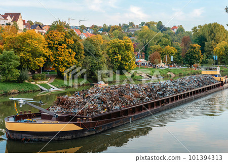 Transportation industry. Ship barge transports scrap metal and sand with gravel. Barge loaded with scrap metal is on the roadstead. Scrap metal transportation by water. Barge laden by metal salvage 101394313
