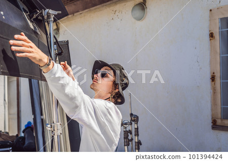 gaffer or the chief electrician in a motion-picture or television production unit set up the lights and light stand on a commercial shoot gaffer or the chief electrician in a motion-picture or television production unit set up the lights and light stand on a commercial shoot 101394424